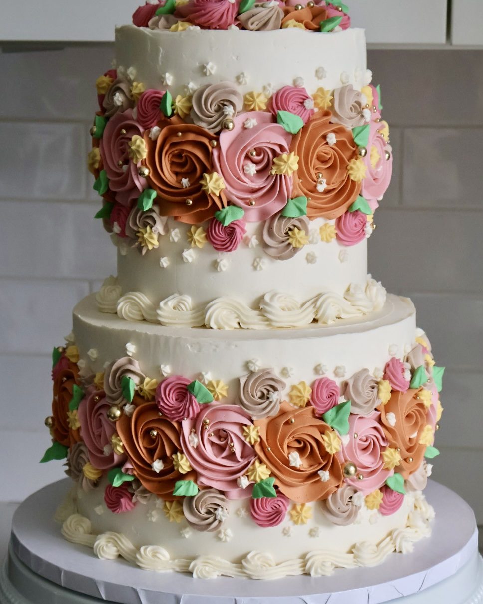 Two-tier cake covered in pink and copper buttercream rosettes