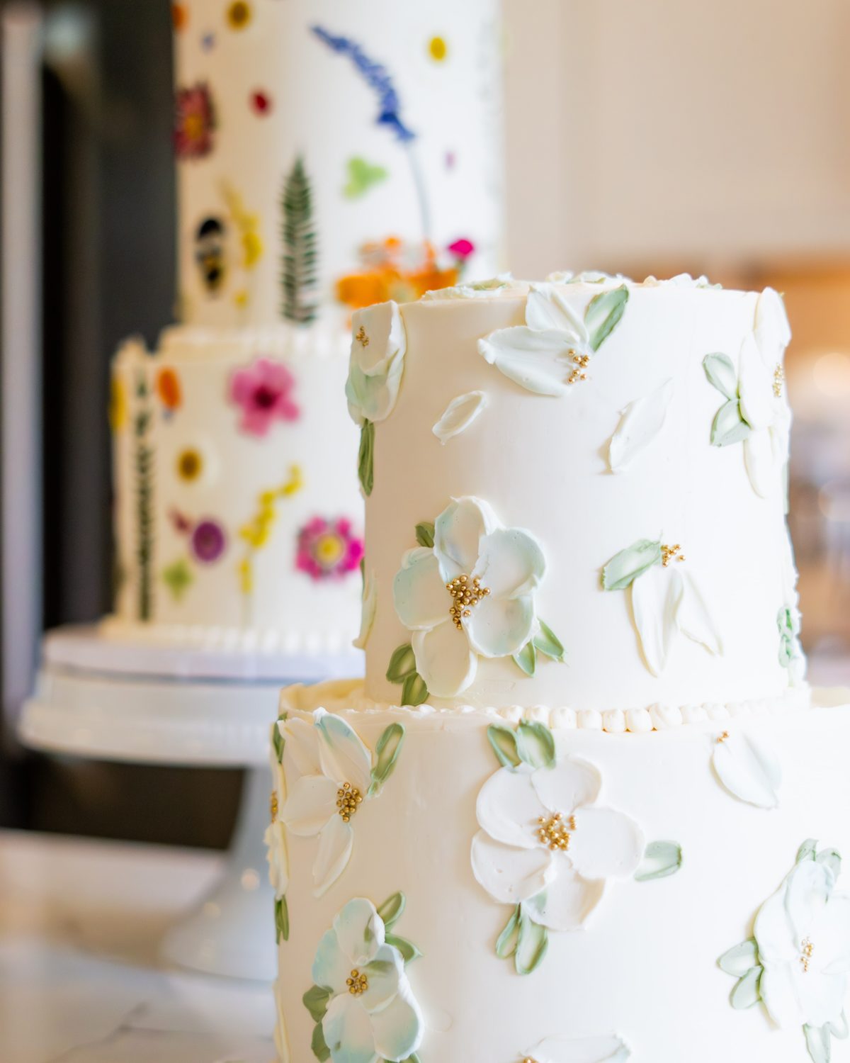 Two-tier white buttercream cake decorated with painted wildflowers