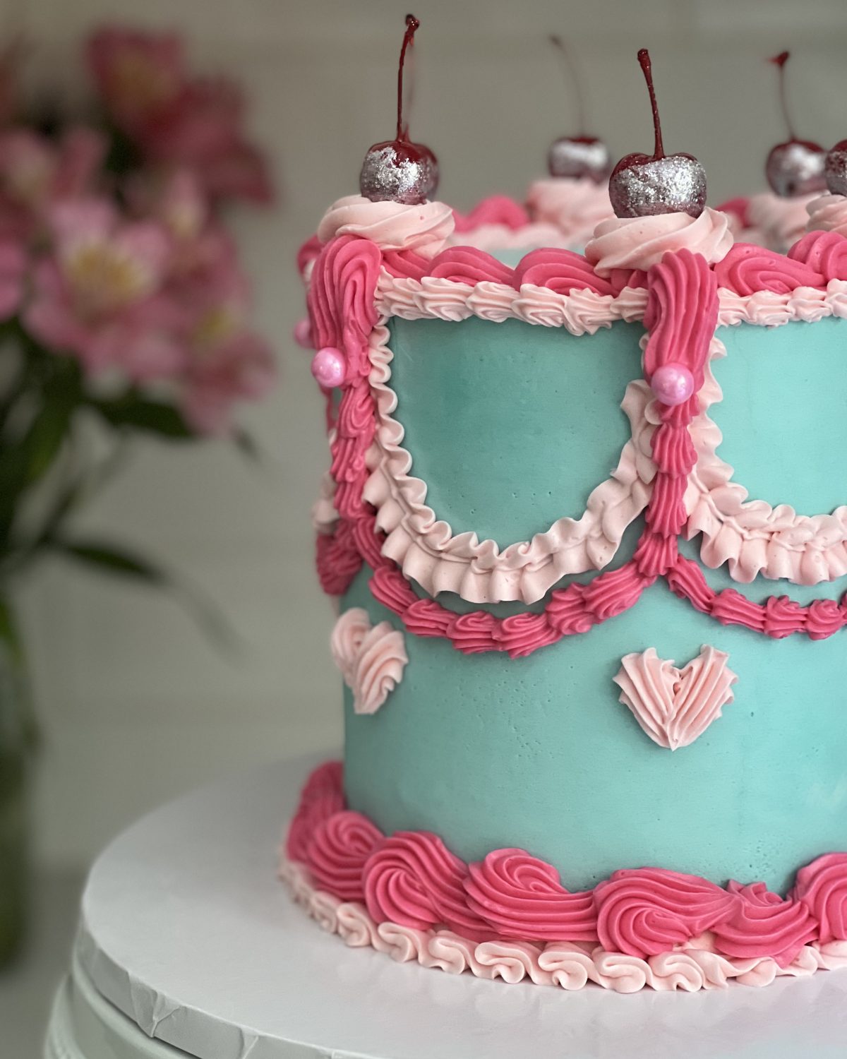 Teal vintage piped cake with pink frills and cherries